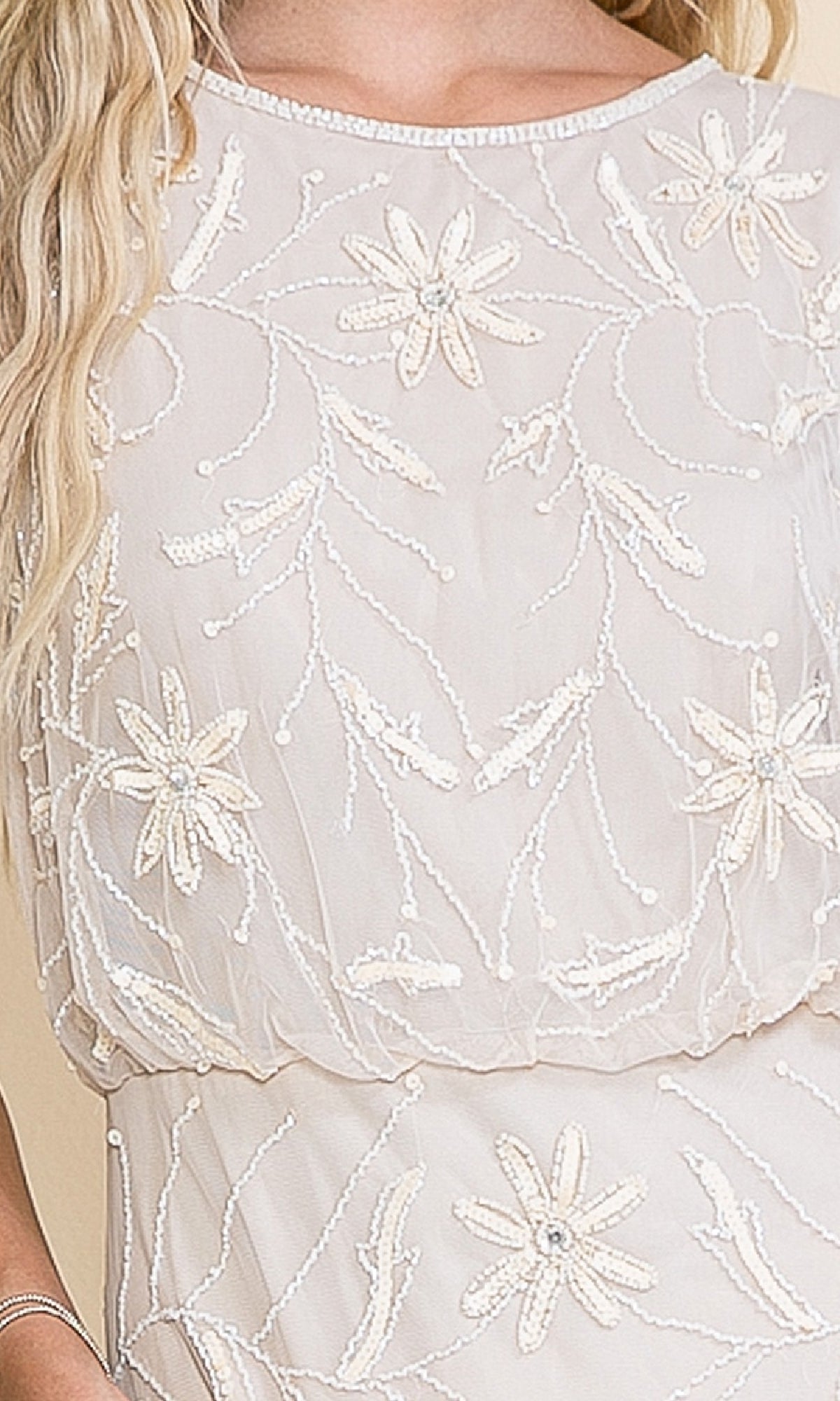 A close-up of the Blouson Long Formal Dress: Amelia Couture IN004, showcasing intricate embroidered floral embellishments and bead detailing on sheer fabric.